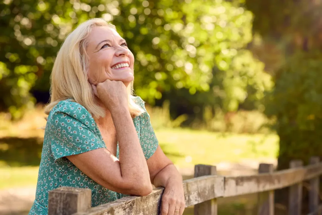 Síntomas y tratamiento de la menopausia 4 síntomas de la menopausia Mujer mayor de 50 años sonriendo al aire libre – síntomas de la menopausia